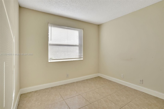 spare room featuring light tile patterned floors and a textured ceiling