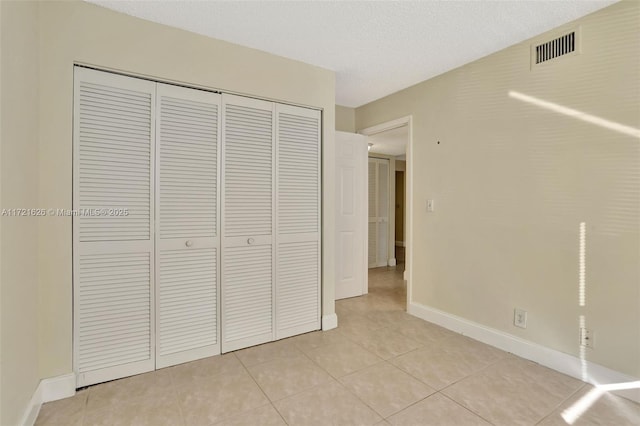 unfurnished bedroom with a textured ceiling, a closet, and light tile patterned flooring