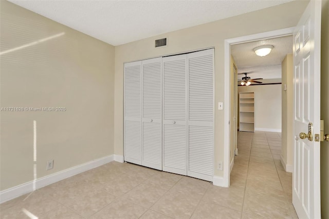 unfurnished bedroom featuring light tile patterned floors, a textured ceiling, and a closet