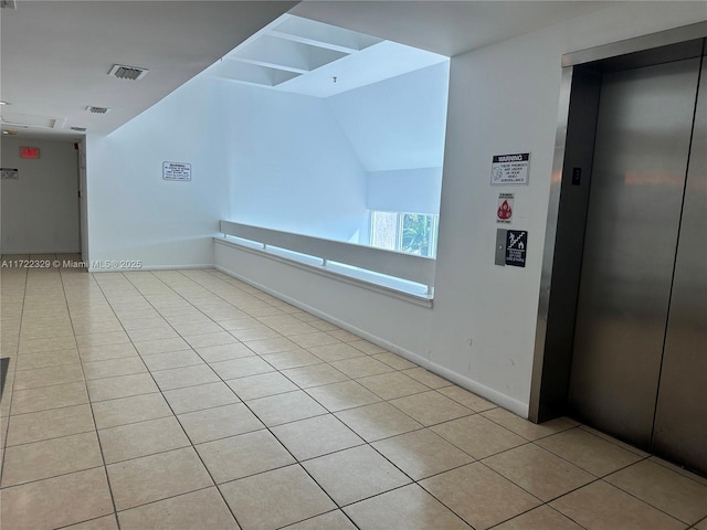 unfurnished room featuring elevator and light tile patterned floors