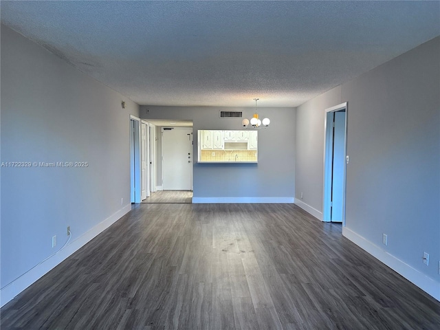 spare room featuring dark hardwood / wood-style flooring, a notable chandelier, and a textured ceiling