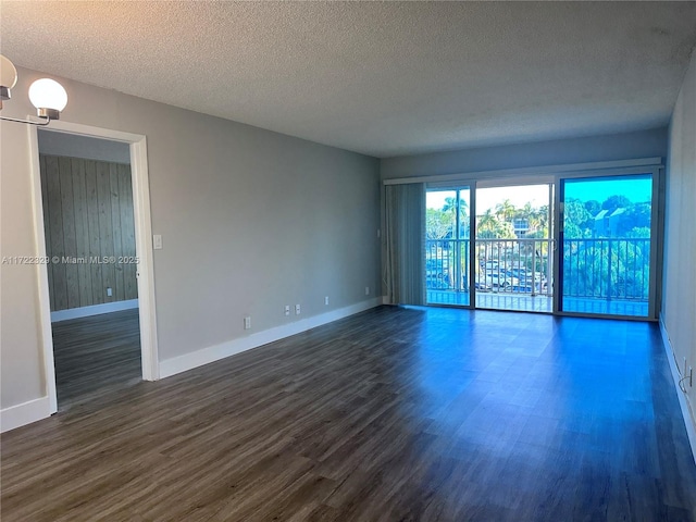 unfurnished room with dark hardwood / wood-style flooring and a textured ceiling