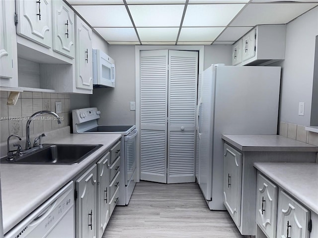 kitchen with white cabinetry, sink, white appliances, and tasteful backsplash