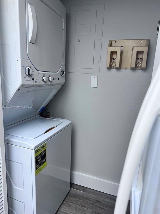 laundry area with stacked washer and dryer, dark hardwood / wood-style flooring, and electric panel