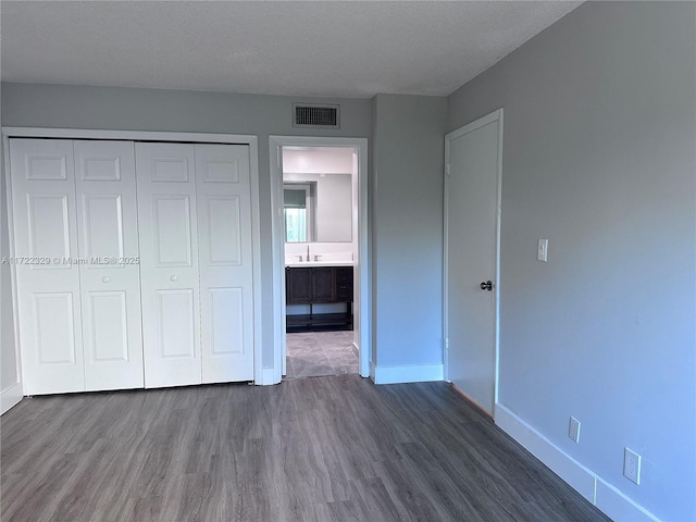 unfurnished bedroom featuring dark hardwood / wood-style flooring, a closet, and a textured ceiling