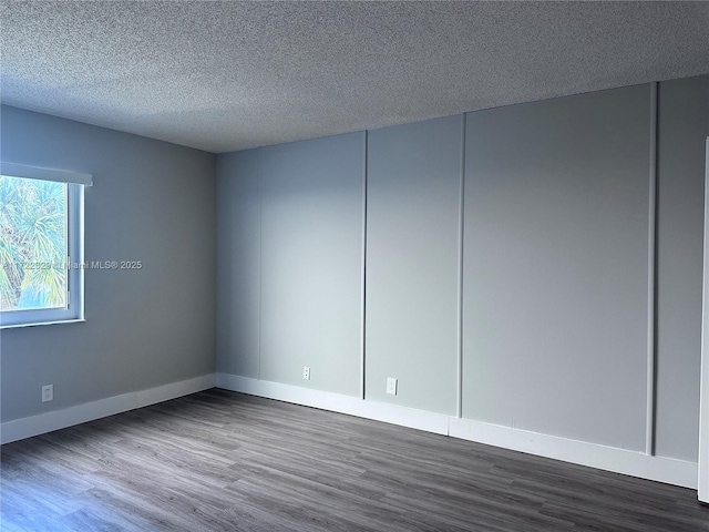 empty room featuring dark hardwood / wood-style flooring and a textured ceiling