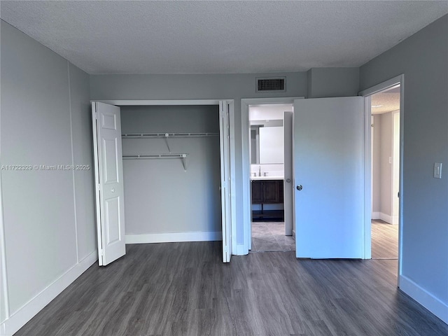 unfurnished bedroom with dark hardwood / wood-style floors, sink, a textured ceiling, and a closet