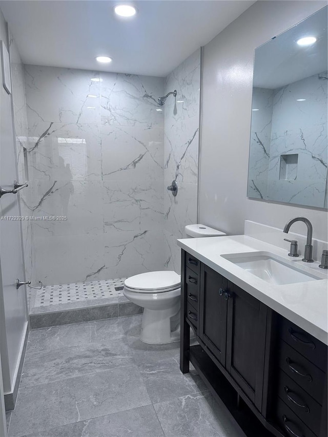 bathroom with vanity, toilet, and a tile shower