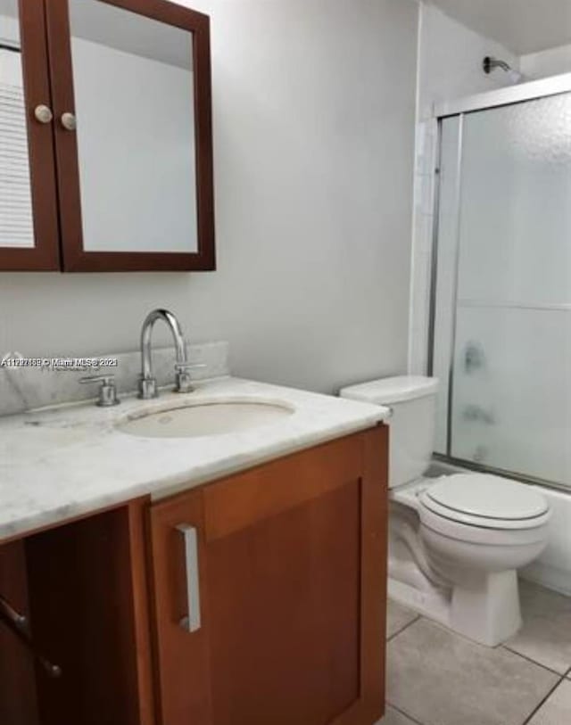 full bathroom with tile patterned floors, vanity, toilet, and enclosed tub / shower combo