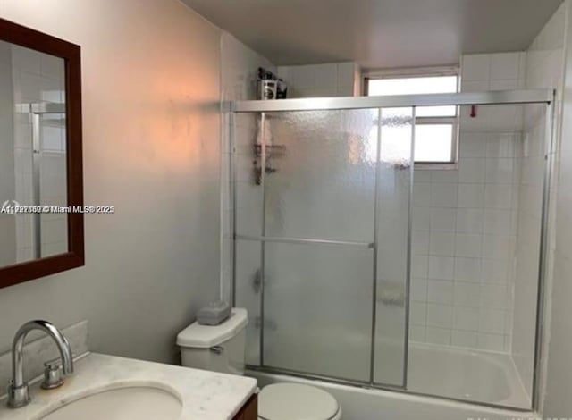 full bathroom featuring vanity, bath / shower combo with glass door, and toilet