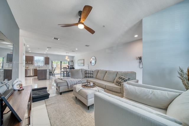 living room featuring ceiling fan, light tile patterned floors, and a textured ceiling