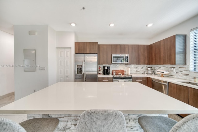 kitchen with a kitchen island, a kitchen bar, appliances with stainless steel finishes, and tasteful backsplash