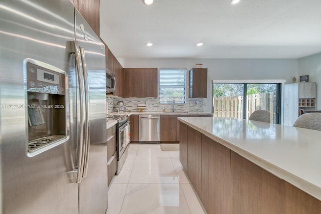 kitchen with backsplash, light tile patterned floors, sink, and appliances with stainless steel finishes