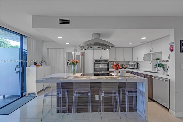 kitchen featuring island exhaust hood, stainless steel appliances, a kitchen island, and sink