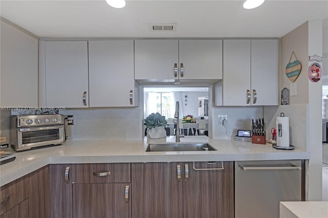 kitchen with stainless steel dishwasher, decorative backsplash, and sink