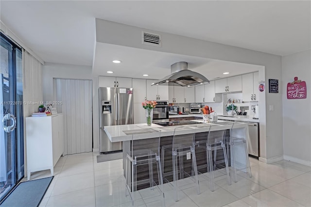 kitchen featuring white cabinetry, light tile patterned floors, island exhaust hood, a kitchen island, and appliances with stainless steel finishes