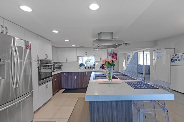 kitchen featuring white cabinets, a wealth of natural light, wall chimney exhaust hood, and appliances with stainless steel finishes