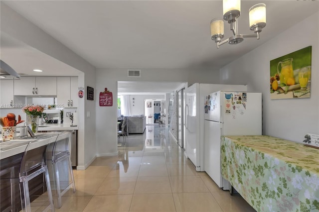 kitchen with white cabinetry, white fridge, a chandelier, decorative light fixtures, and light tile patterned flooring