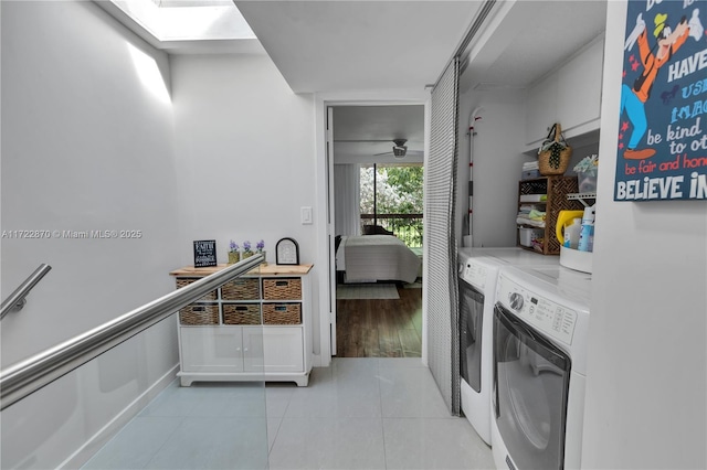 washroom featuring washer and dryer, ceiling fan, light tile patterned floors, and a skylight