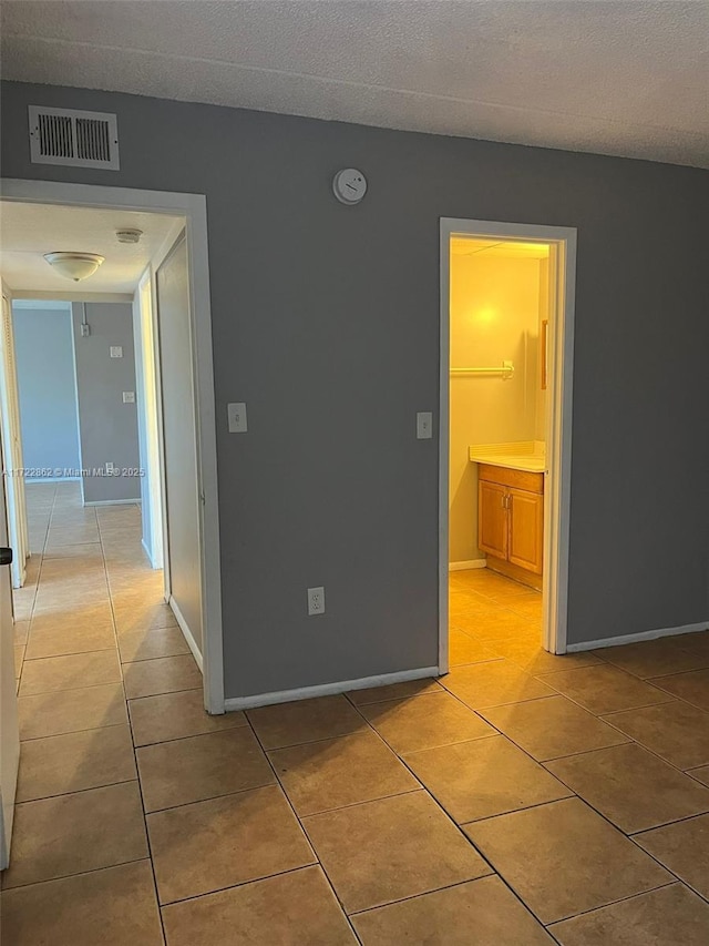 empty room with light tile patterned floors and a textured ceiling