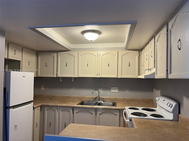 kitchen with sink, ventilation hood, white appliances, a tray ceiling, and white cabinets