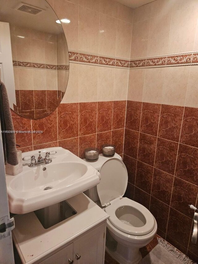 bathroom featuring sink, toilet, and tile walls