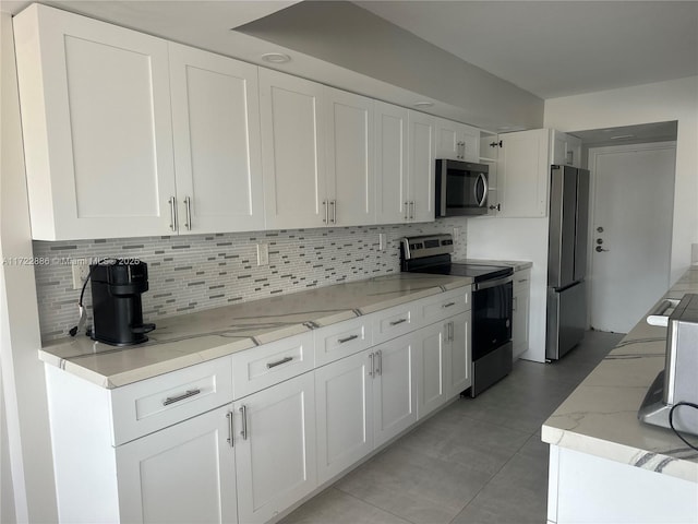 kitchen featuring backsplash, light stone countertops, stainless steel appliances, and white cabinetry