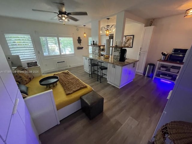 living room featuring dark hardwood / wood-style floors, a wall unit AC, and ceiling fan