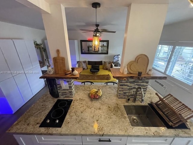 kitchen with sink, ceiling fan, white cabinetry, light stone countertops, and black electric cooktop