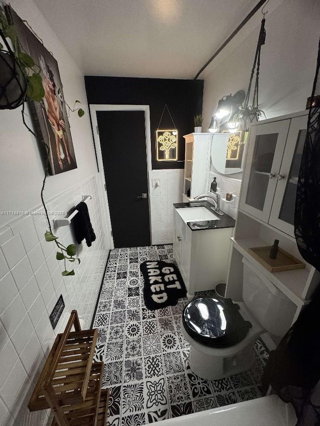 kitchen featuring tile patterned flooring, sink, tile walls, and white cabinets