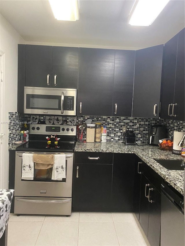 kitchen featuring sink, stainless steel appliances, tasteful backsplash, light stone counters, and light tile patterned flooring