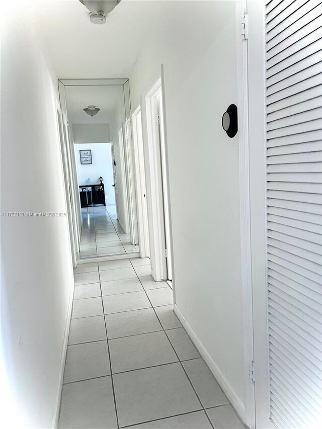 corridor with light tile patterned floors and baseboards
