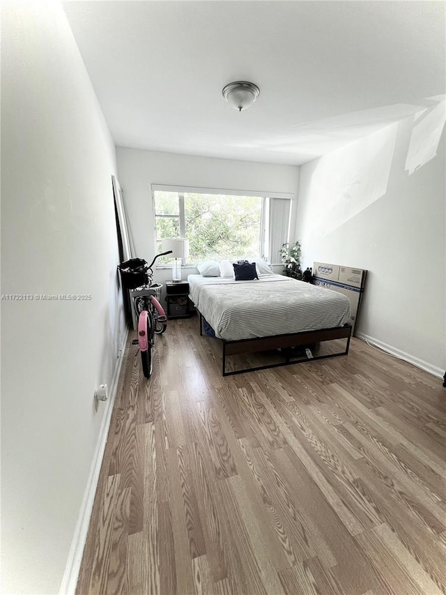 bedroom with baseboards and wood finished floors