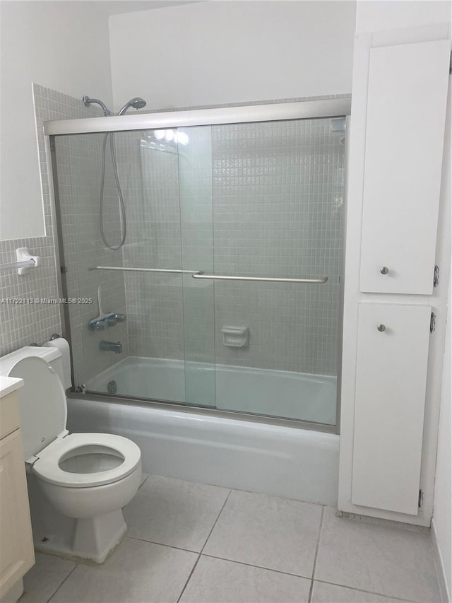 full bathroom featuring tile patterned flooring, vanity, toilet, and bath / shower combo with glass door