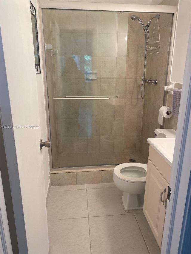 bathroom featuring tile patterned floors, vanity, a shower with shower door, and toilet