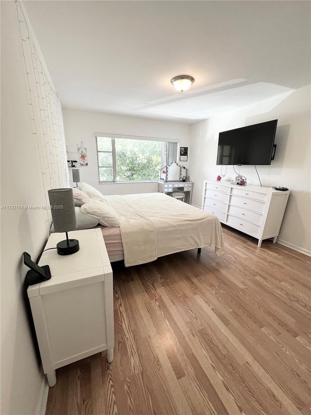 bedroom with baseboards and wood finished floors