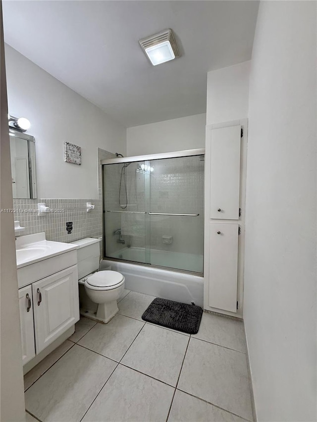 full bathroom with enclosed tub / shower combo, toilet, tile walls, tile patterned floors, and vanity