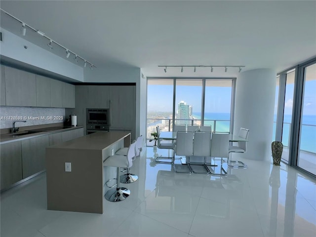 kitchen featuring a center island, stainless steel microwave, sink, decorative backsplash, and light tile patterned floors