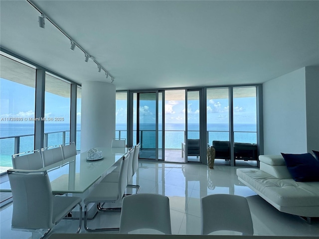 dining room featuring light tile patterned floors, a water view, and expansive windows