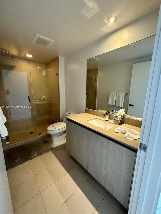 bathroom with tile patterned flooring, vanity, toilet, and an enclosed shower