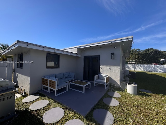 rear view of property featuring a yard, a patio area, fence, and stucco siding