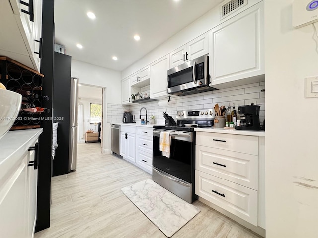 kitchen featuring appliances with stainless steel finishes, white cabinets, light countertops, and backsplash