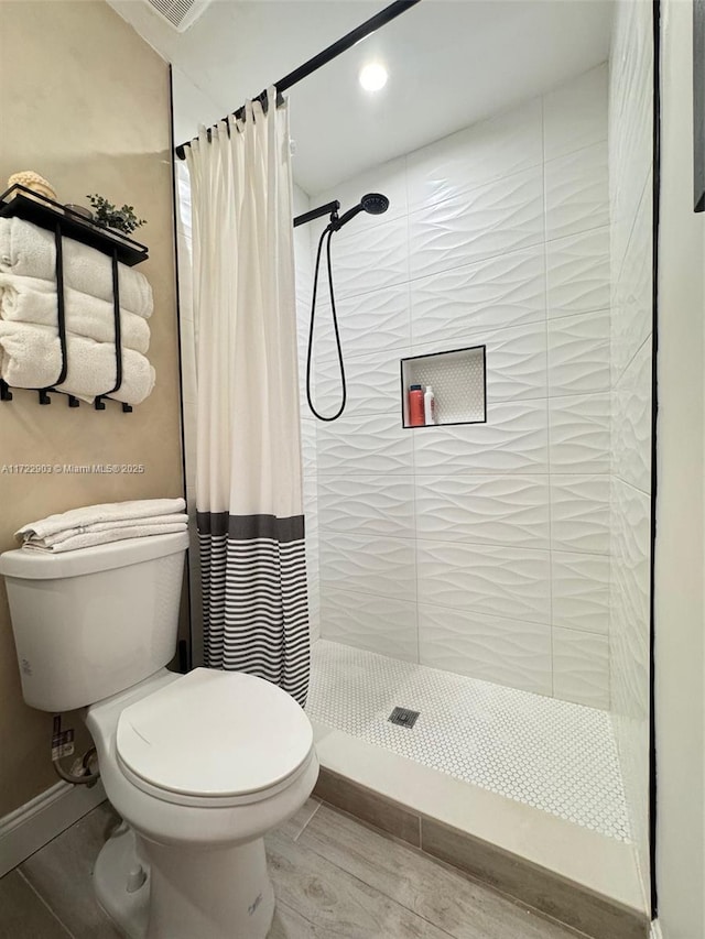 full bath with baseboards, a shower stall, and toilet