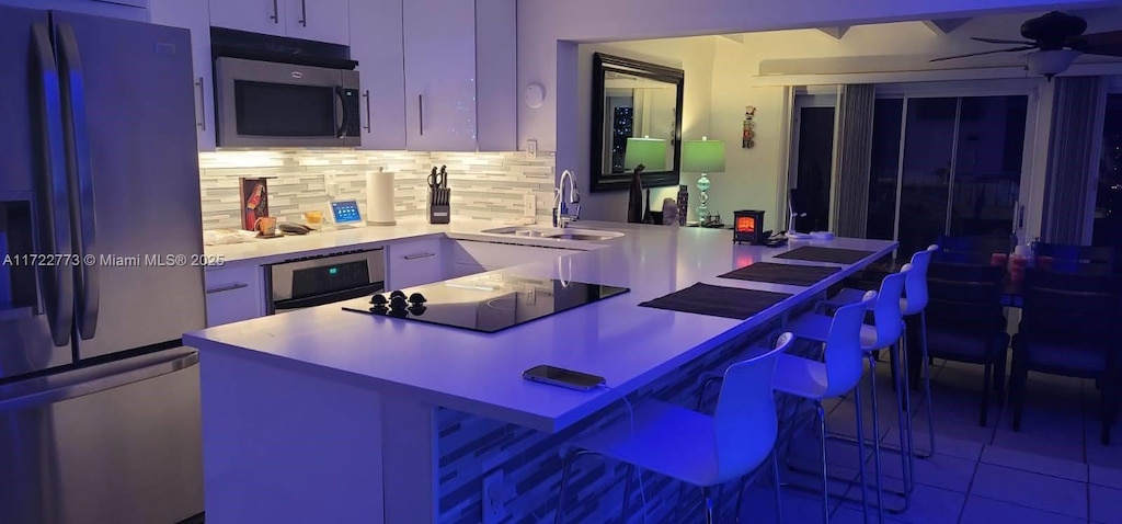 kitchen with a breakfast bar area, kitchen peninsula, sink, and appliances with stainless steel finishes