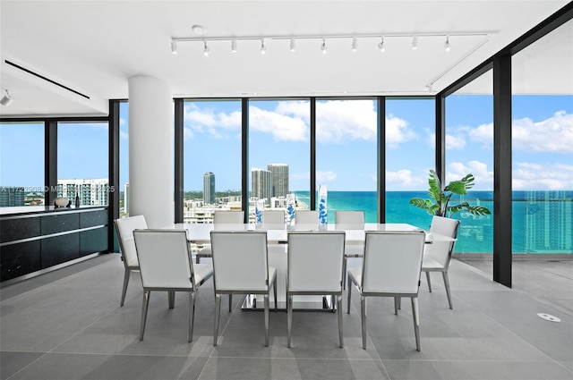 tiled dining space with expansive windows, a water view, and a healthy amount of sunlight