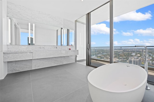 bathroom with a washtub, a wall of windows, and vanity