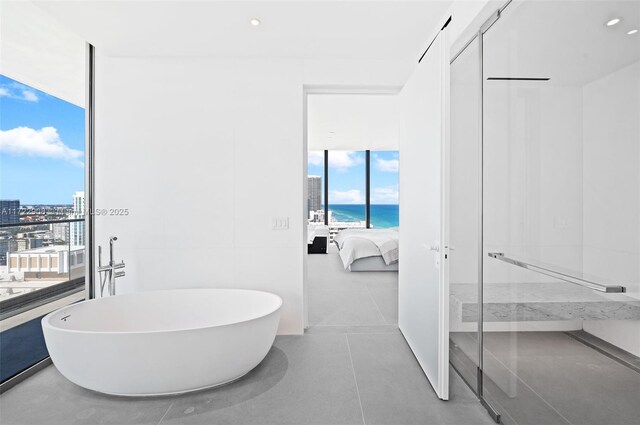 bathroom featuring a water view, expansive windows, and a tub