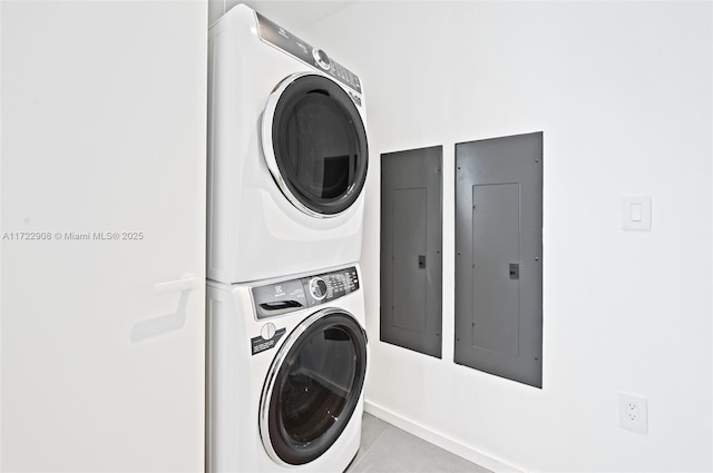 clothes washing area featuring electric panel and stacked washer / drying machine