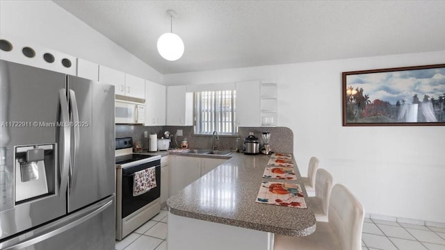 kitchen with white appliances, vaulted ceiling, sink, white cabinetry, and light tile patterned flooring