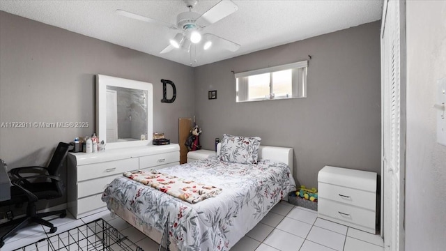 bedroom featuring ceiling fan, light tile patterned floors, and a textured ceiling